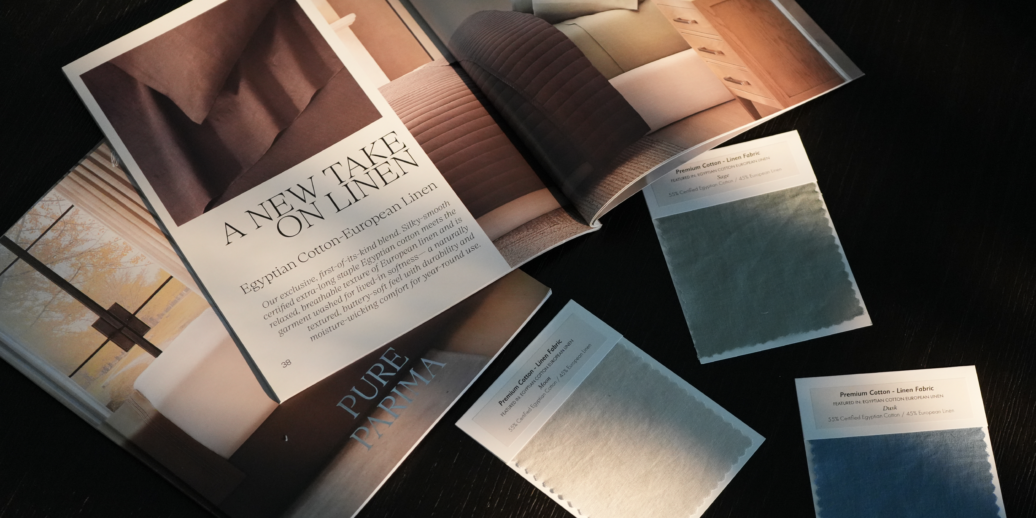 An open interior design magazine or catalog spread on a dark surface, with several small fabric or material swatch cards placed around it. The visible text includes 'A NEW TAKE ON LINEN' and 'PURE PARIMA.