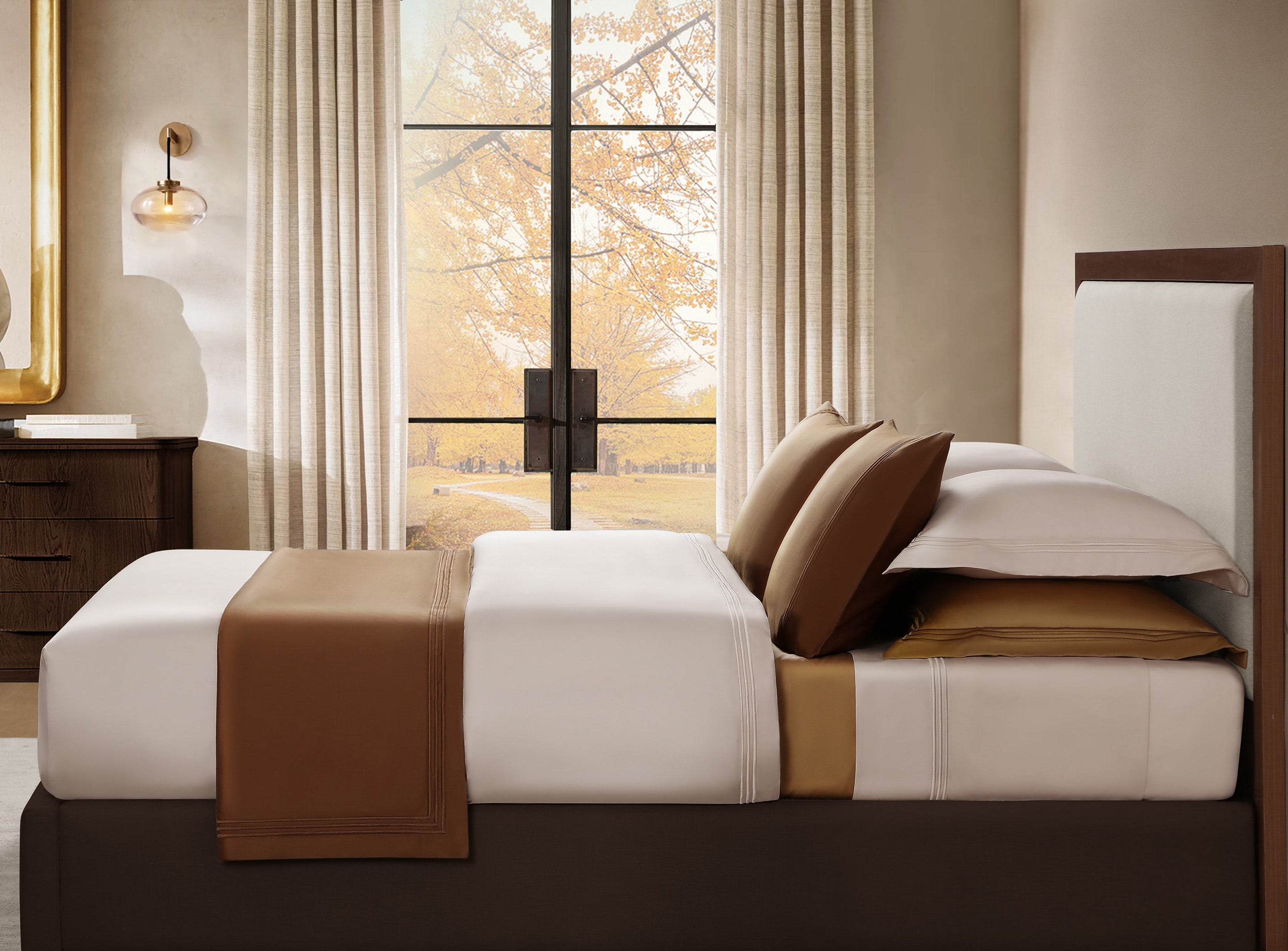 Bedroom with a bed featuring brown and white bedding, large window, and decorative pillows.