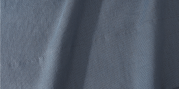 A close-up of draped slate blue fabric with a fine textured weave.